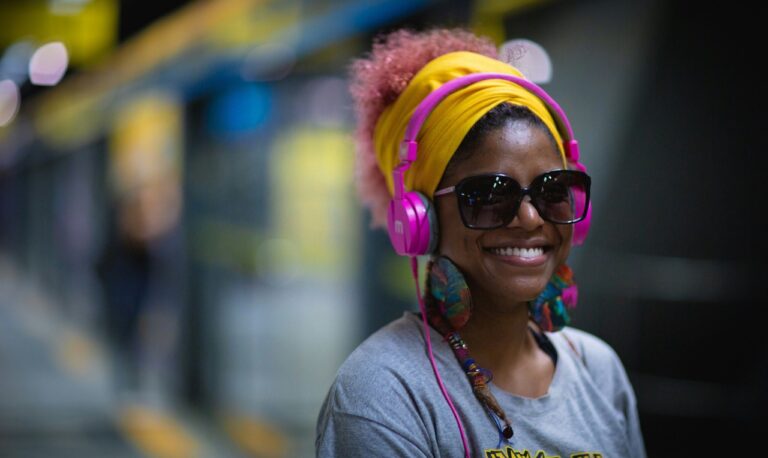 Woman smiling with a headphone on showing why its one of the most important travel gadgets